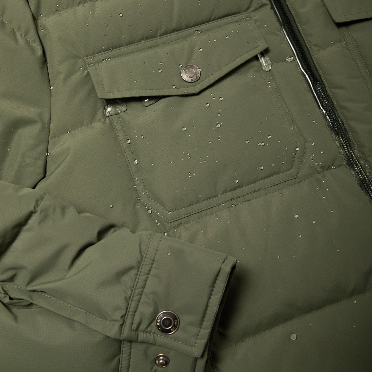Katin OTG Summit Hooded Down Puffer in Thyme with a stacked fill pattern, waterproof detail pocket #color_thyme