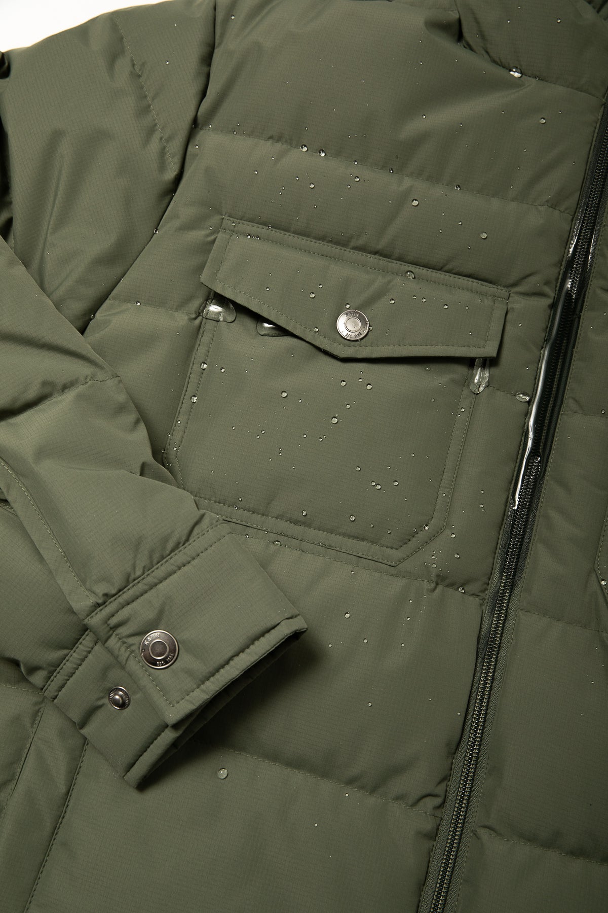 Katin OTG Summit Hooded Down Puffer in Thyme with a stacked fill pattern, detail pocket, front #color_thyme