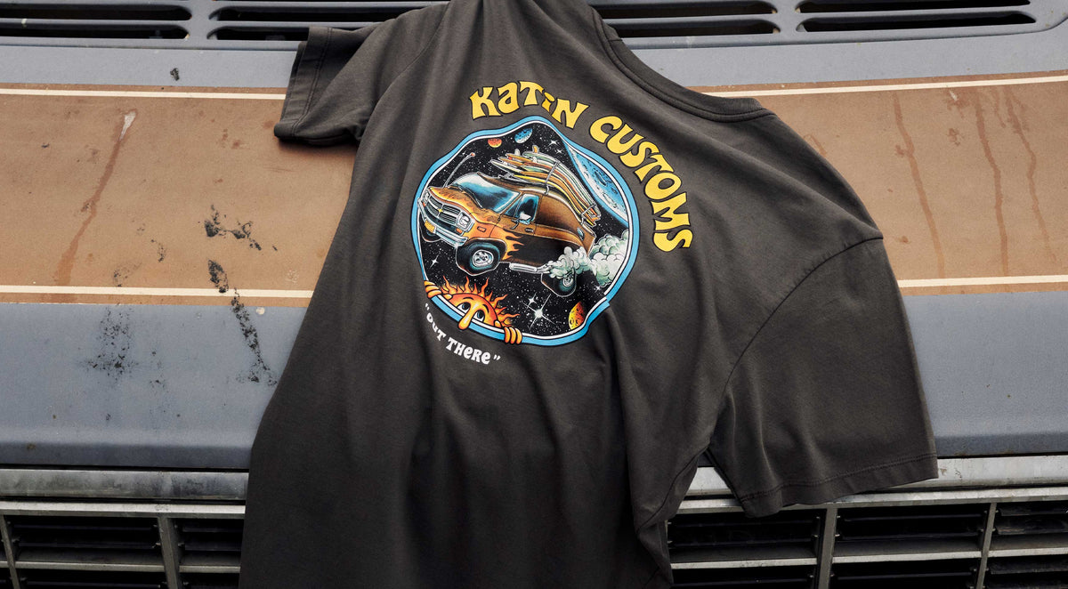 Vantasy Tee draped across a vintage truck hood, showing the “Katin Customs” van-in-space back graphic